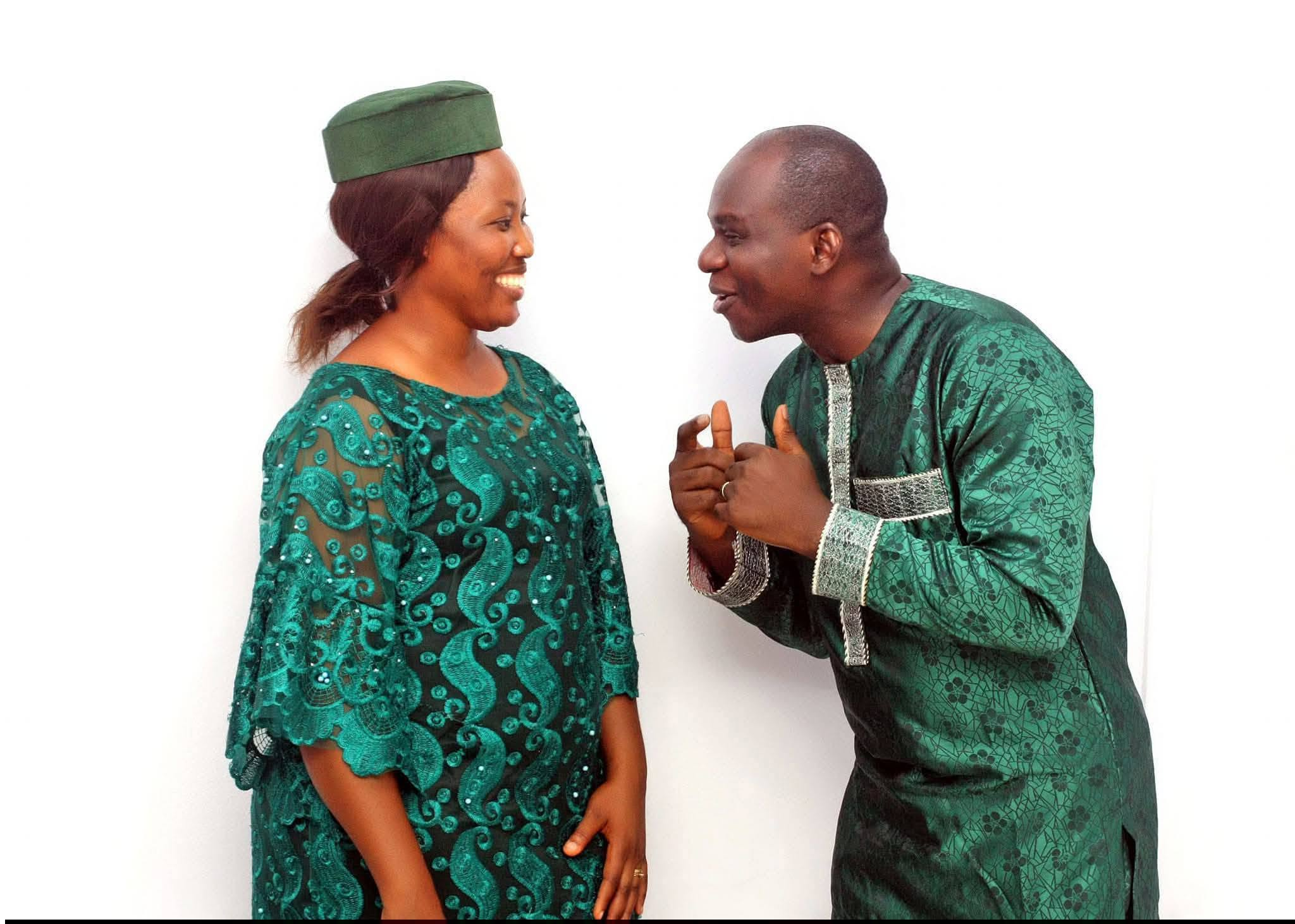 A. T. Adenekan laughing together with his wife, both dressed in matching emerald green attire
